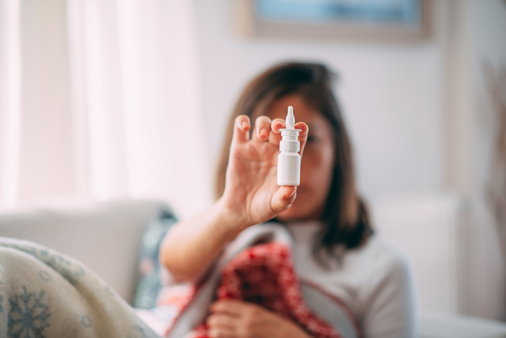 Woman holding out a bottle of nasal spray