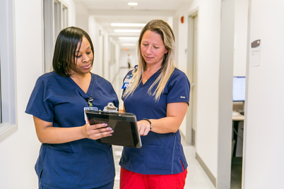 two nurses reading a clipboard