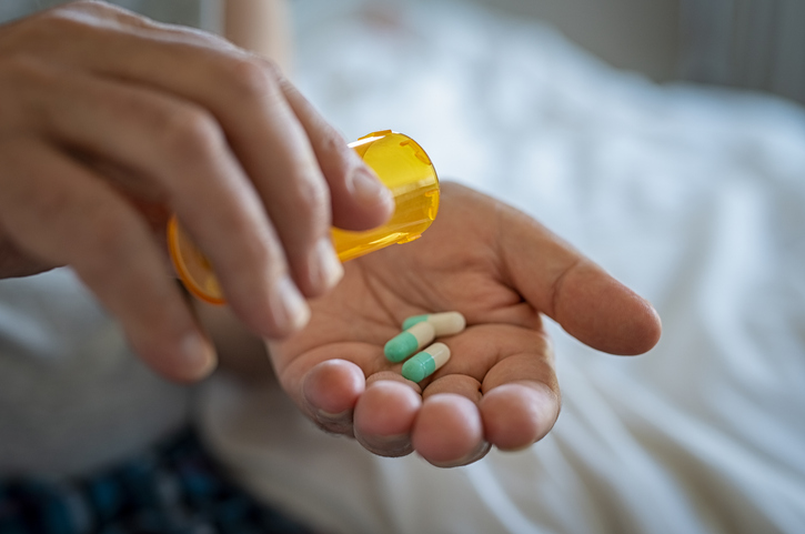 Closeup of man hand pouring capsules from a pill bottle into hand