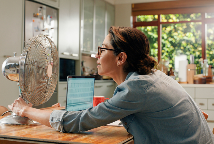 Woman sitting in front of a fan at the kitchen table