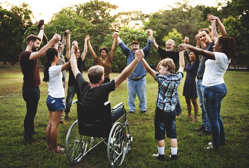 Group of people outdoors in a circle holding hands.