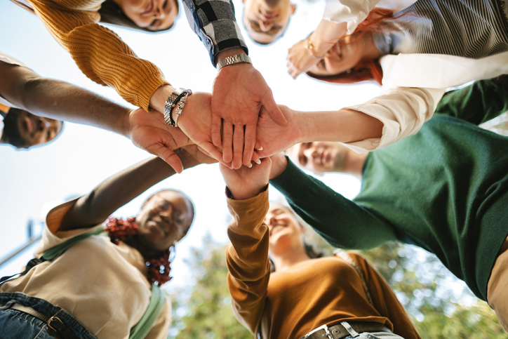 Group of people joining hands in a team circle.