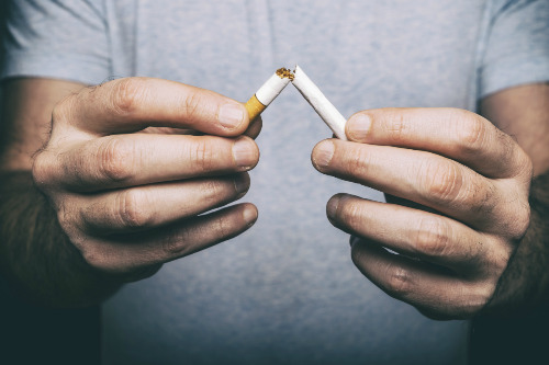 Closeup view of a man's hands breaking a cigarette in half. 