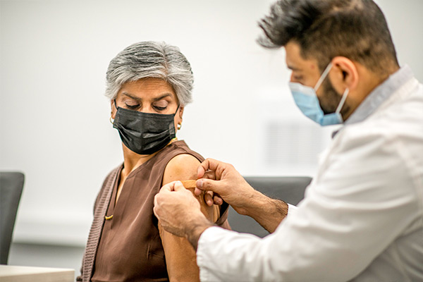 Provider placing a bandaid on a patient, after the patient receives a flu vaccine.